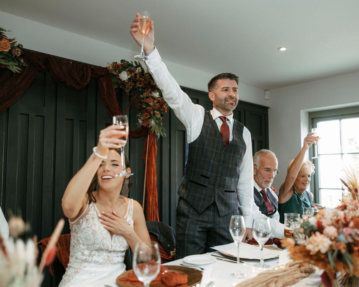 Wedding reception toast with guests raising glasses in celebration.