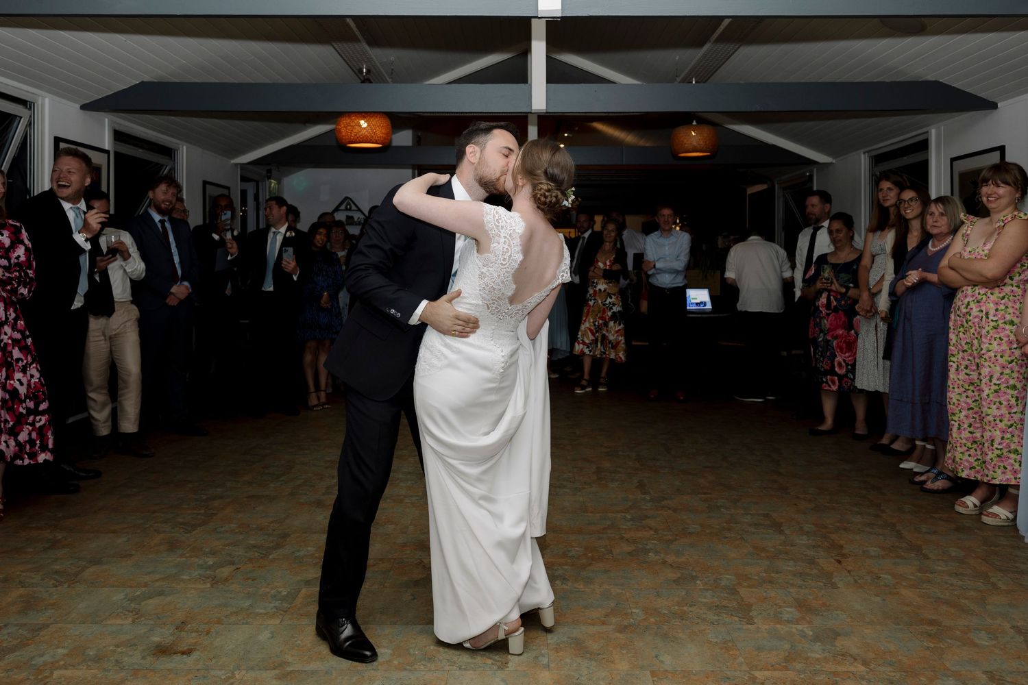 Bride and groom share their first dance at wedding reception while guests watch in elegant venue.