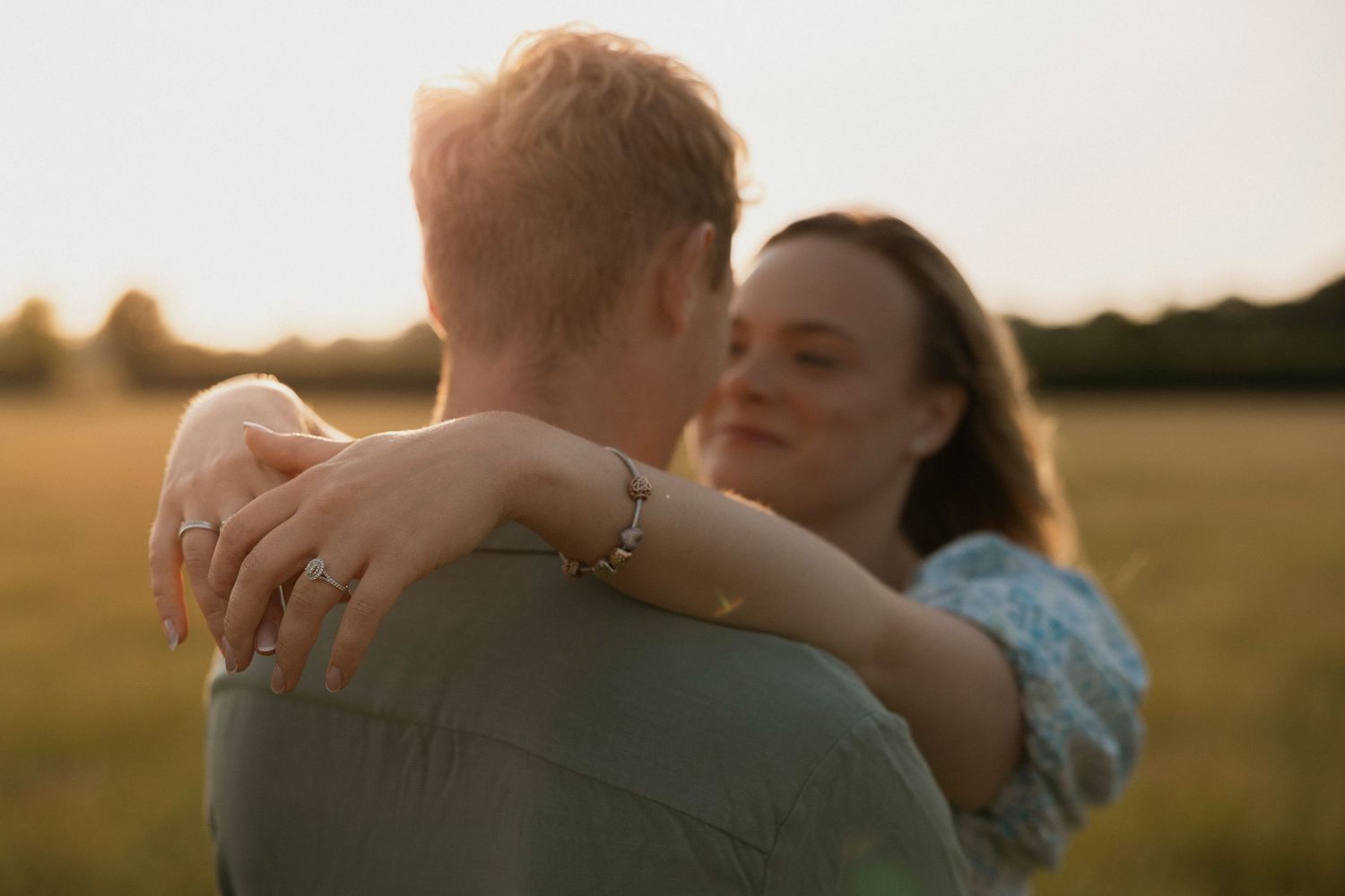A couple embraces in a golden field during sunset creating a romantic silhouette against the warm sky.