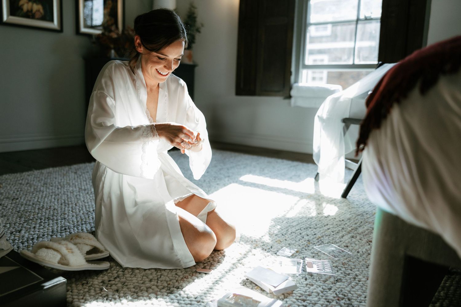Morning light streams through a window onto a carpeted floor where someone in a white robe sits looking down.