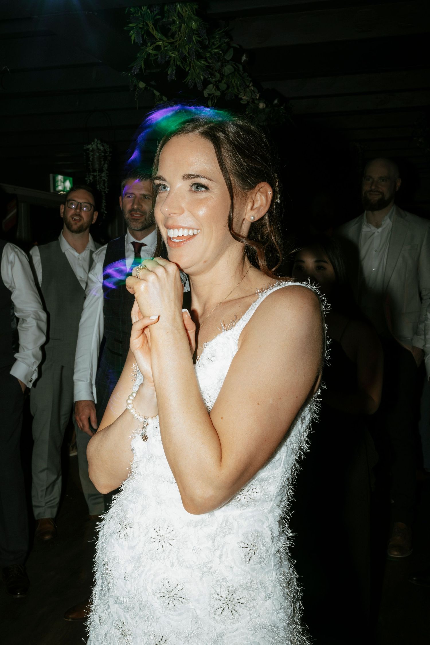 Wedding celebration at night with dancing under colorful lights.