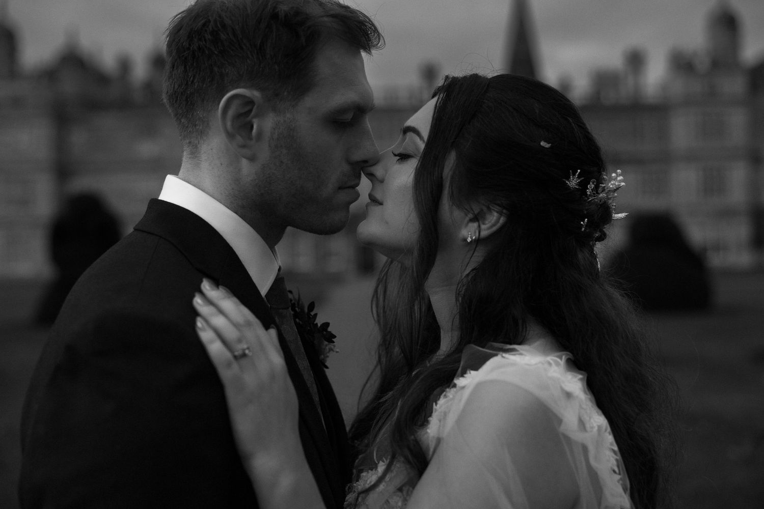 Black and white wedding photo of bride and groom sharing an intimate moment, nearly kissing outdoors.
