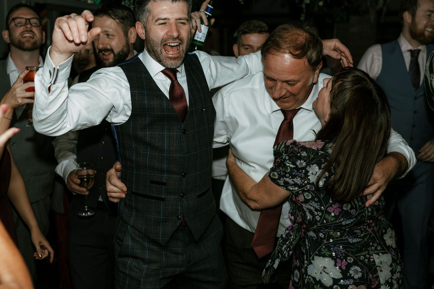 Guests dancing and celebrating joyfully at a lively wedding reception party.