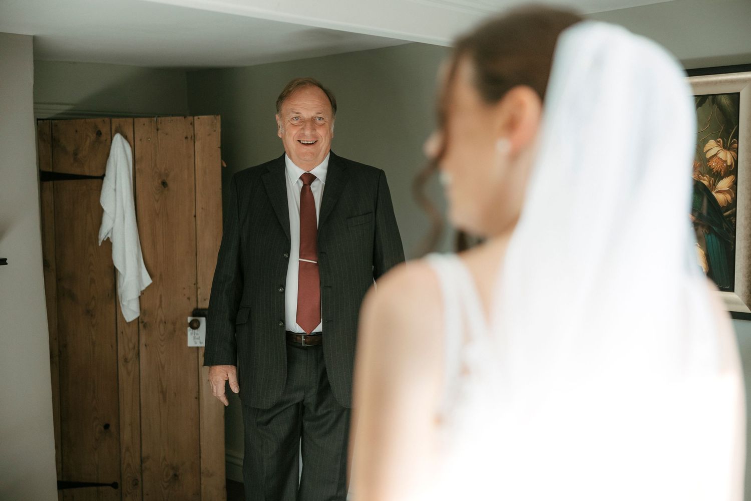 A touching emotional moment between a bride and someone dressed in a suit in a dimly lit room.