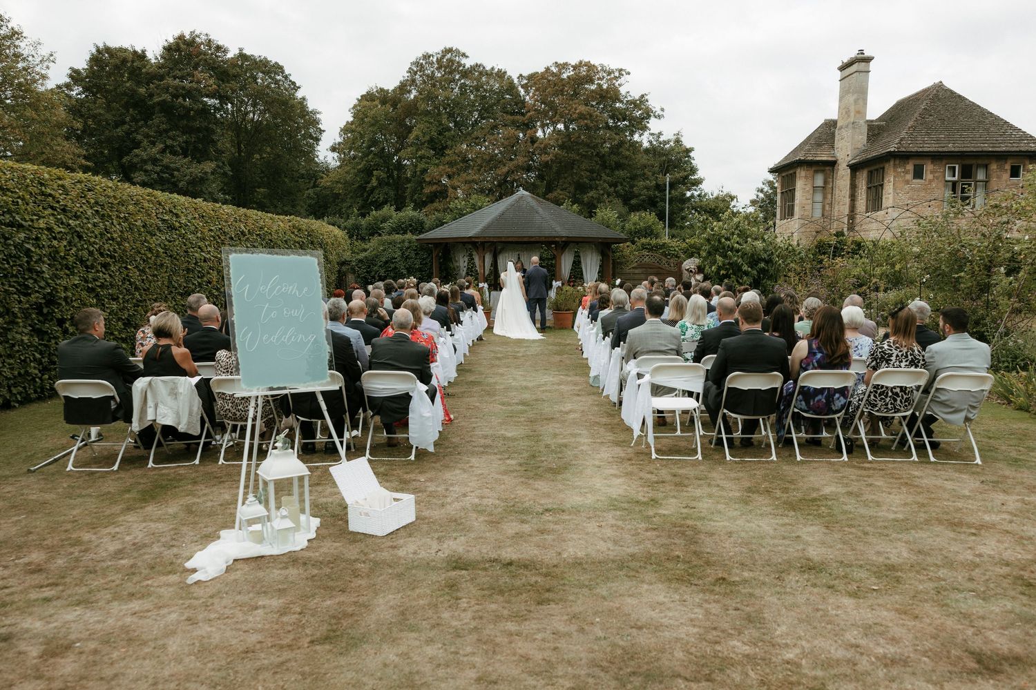 Outdoor garden wedding ceremony with guests seated in rows facing the altar at an elegant venue.
