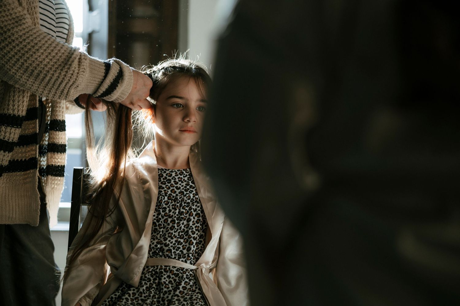 A photographer captures a person wearing a polka dot dress in soft, natural window light.