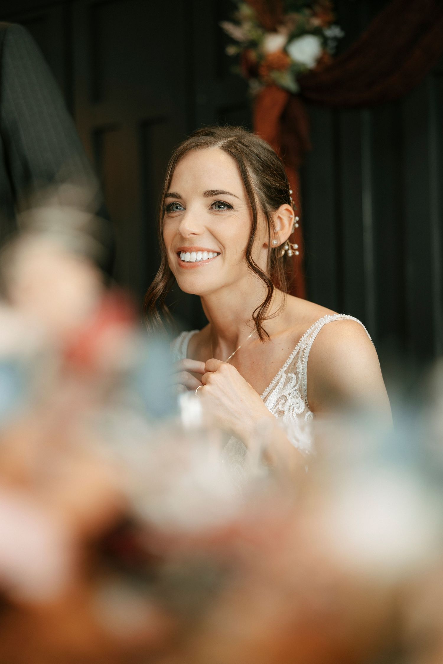 A radiant bride in a lace dress smiles joyfully during her wedding celebration.