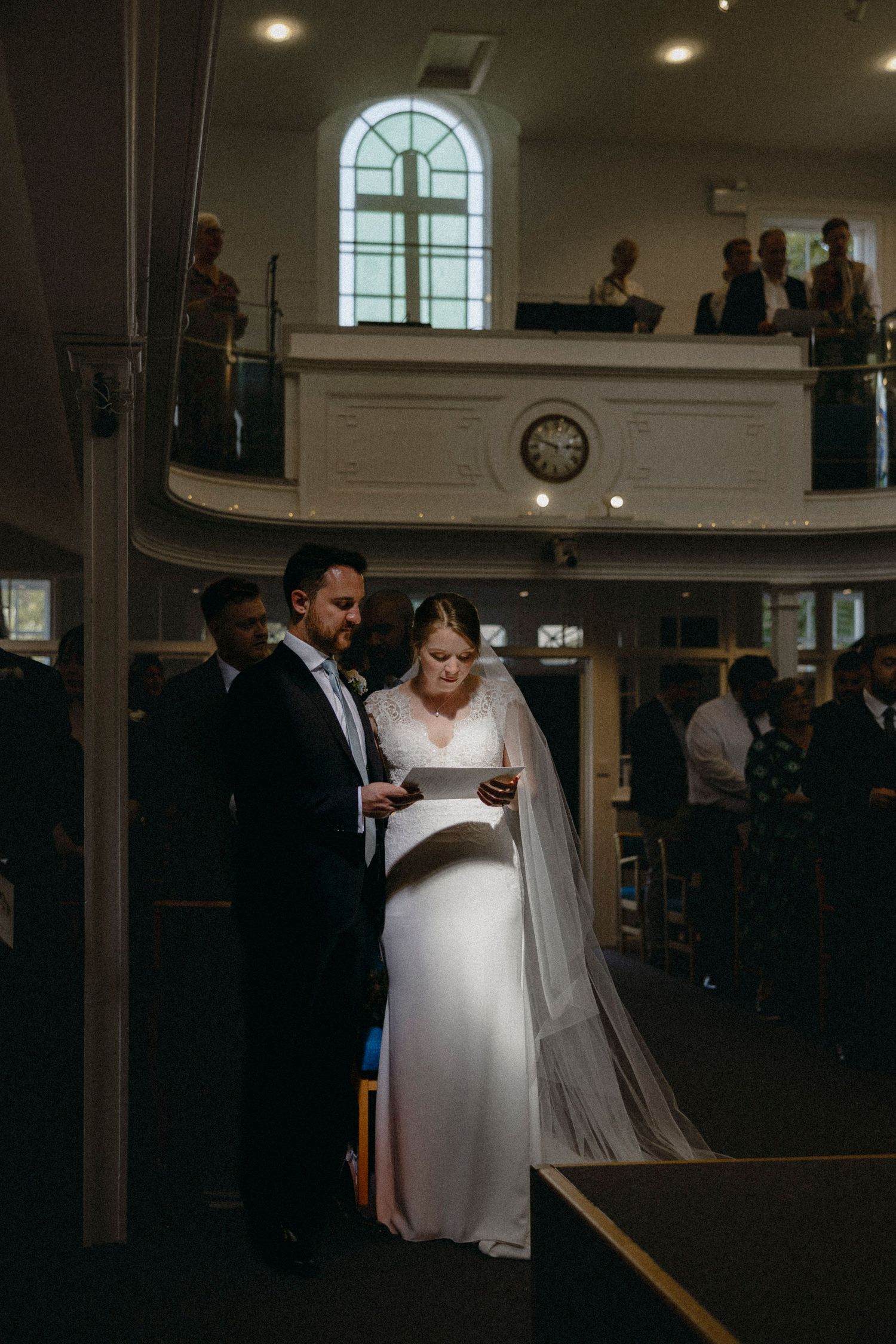 Bride and groom reading vows together in a elegant church ceremony, bride wearing white gown and veil.