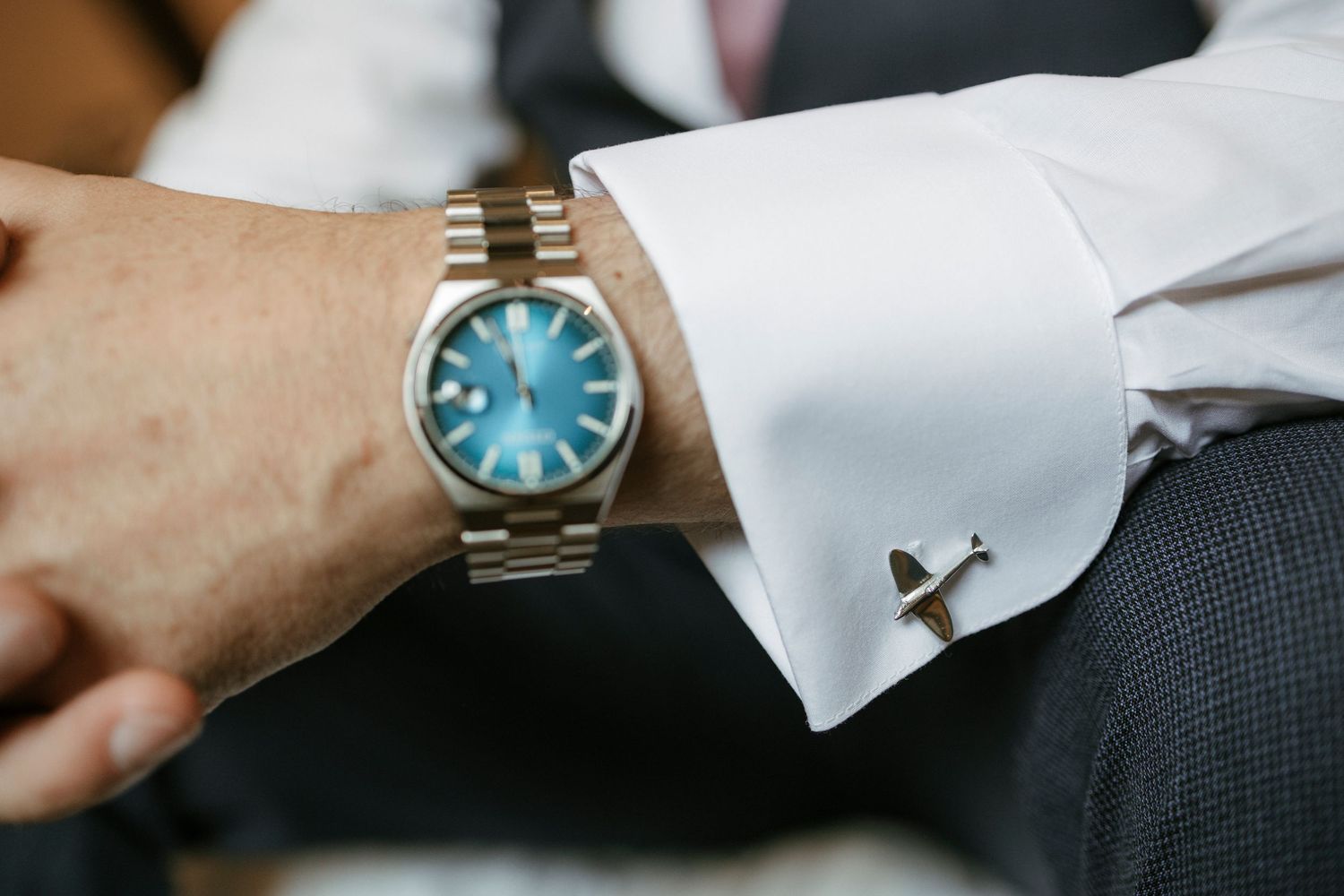 Groom wearing blue dial Rolex watch and cufflinks on wedding day.