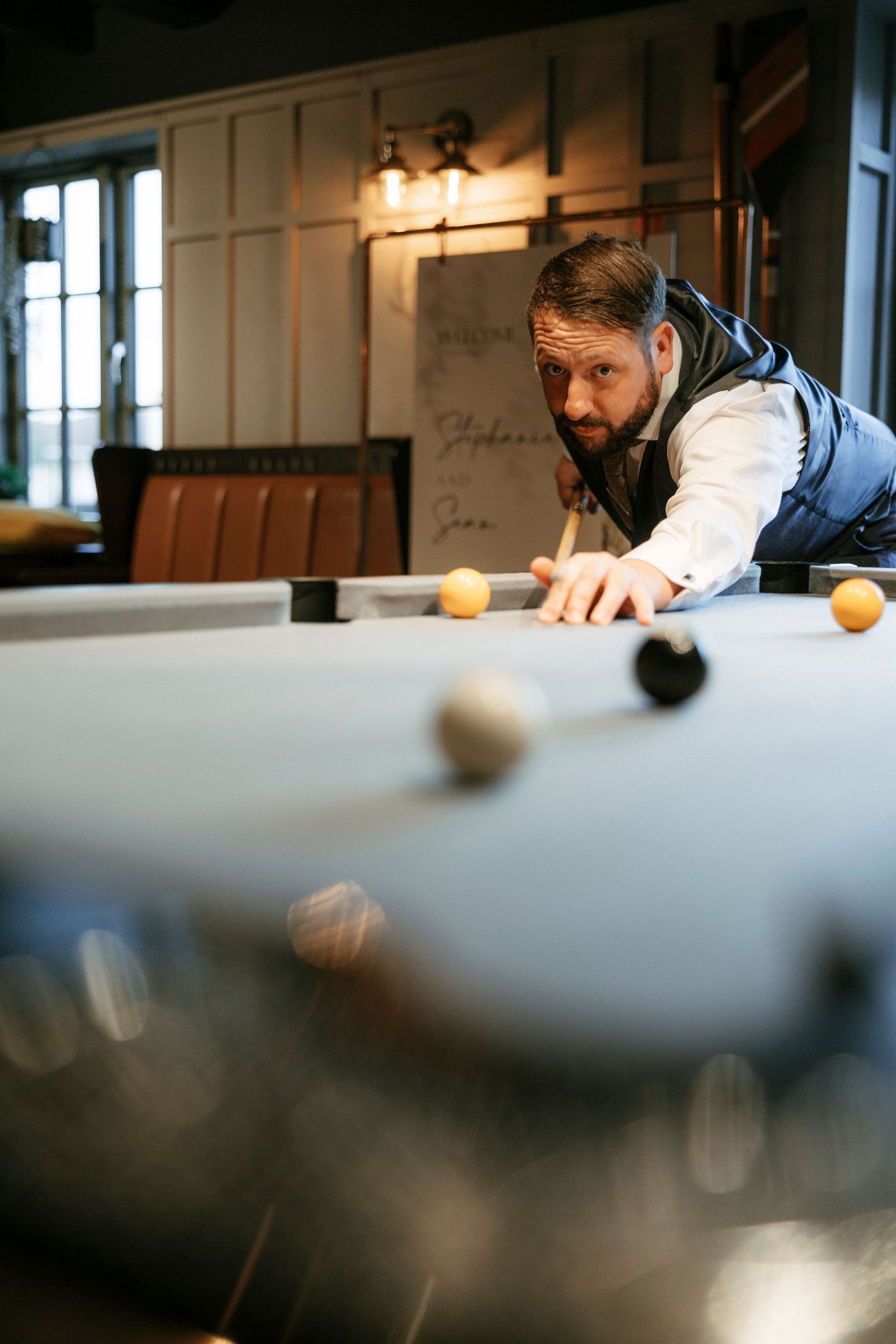 Guest playing pool at an event venue with moody lighting and industrial decor.