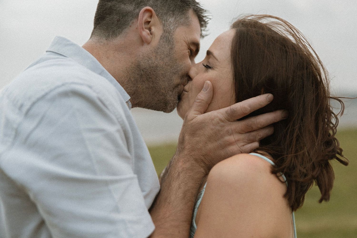 Intimate moment between couple sharing a passionate kiss outdoors.