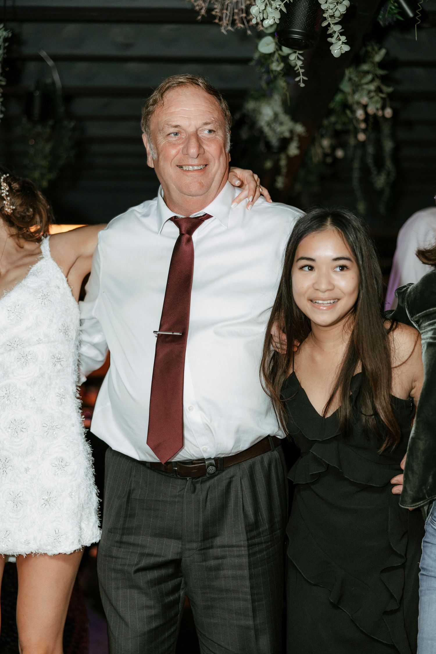 Wedding reception guests posing together under hanging floral decorations.