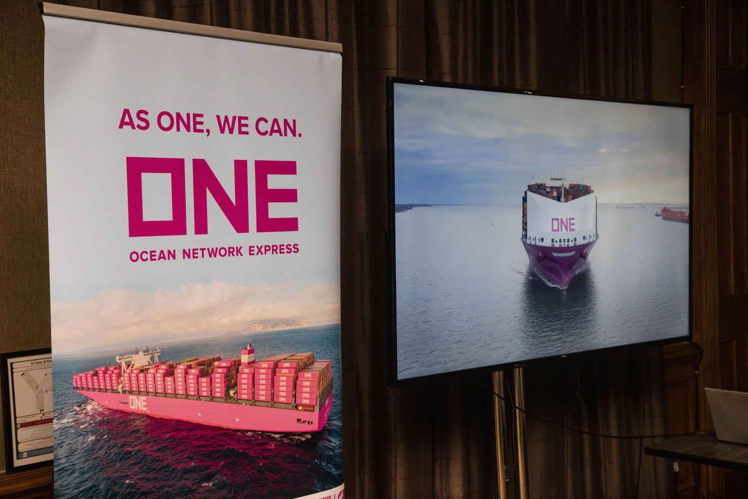 Ocean Network Express shipping company brand display showing ONE logo and container ship images on wall panels.