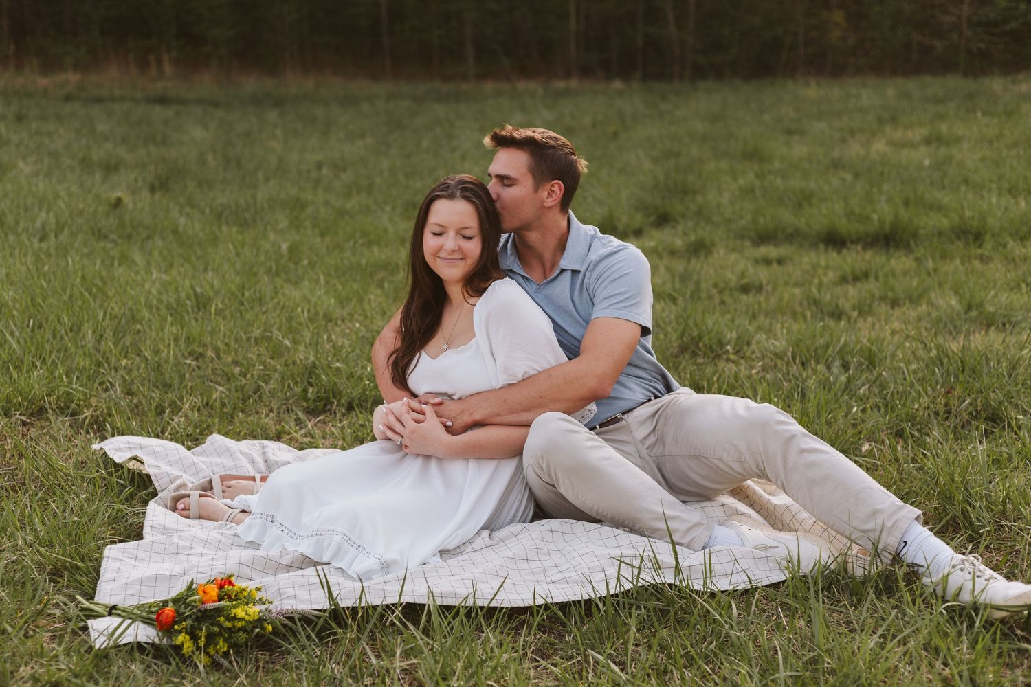 Couple embracing each other on a blanket in a field