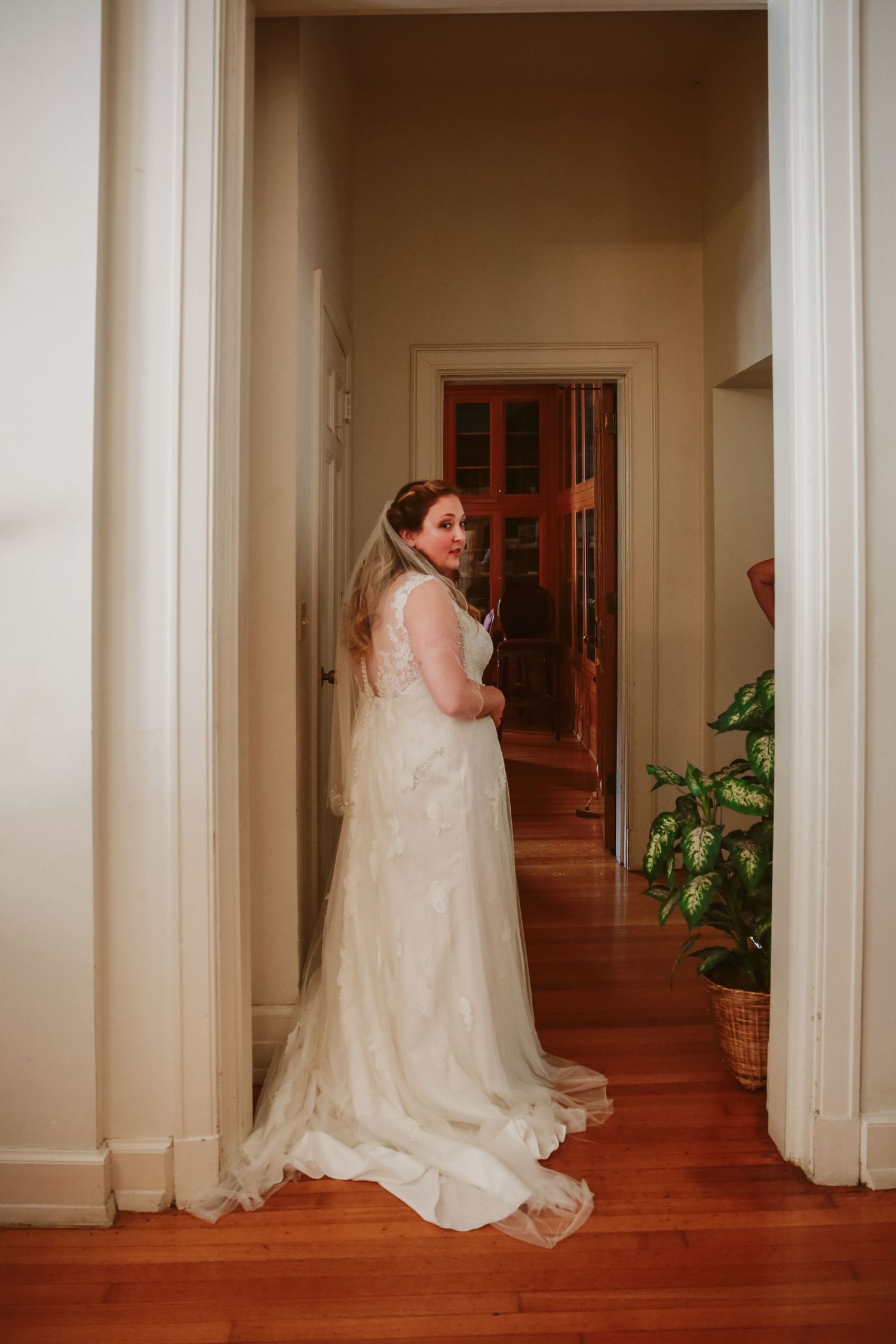 Bride standing in a doorway looking back over her shoulder in her wedding dress