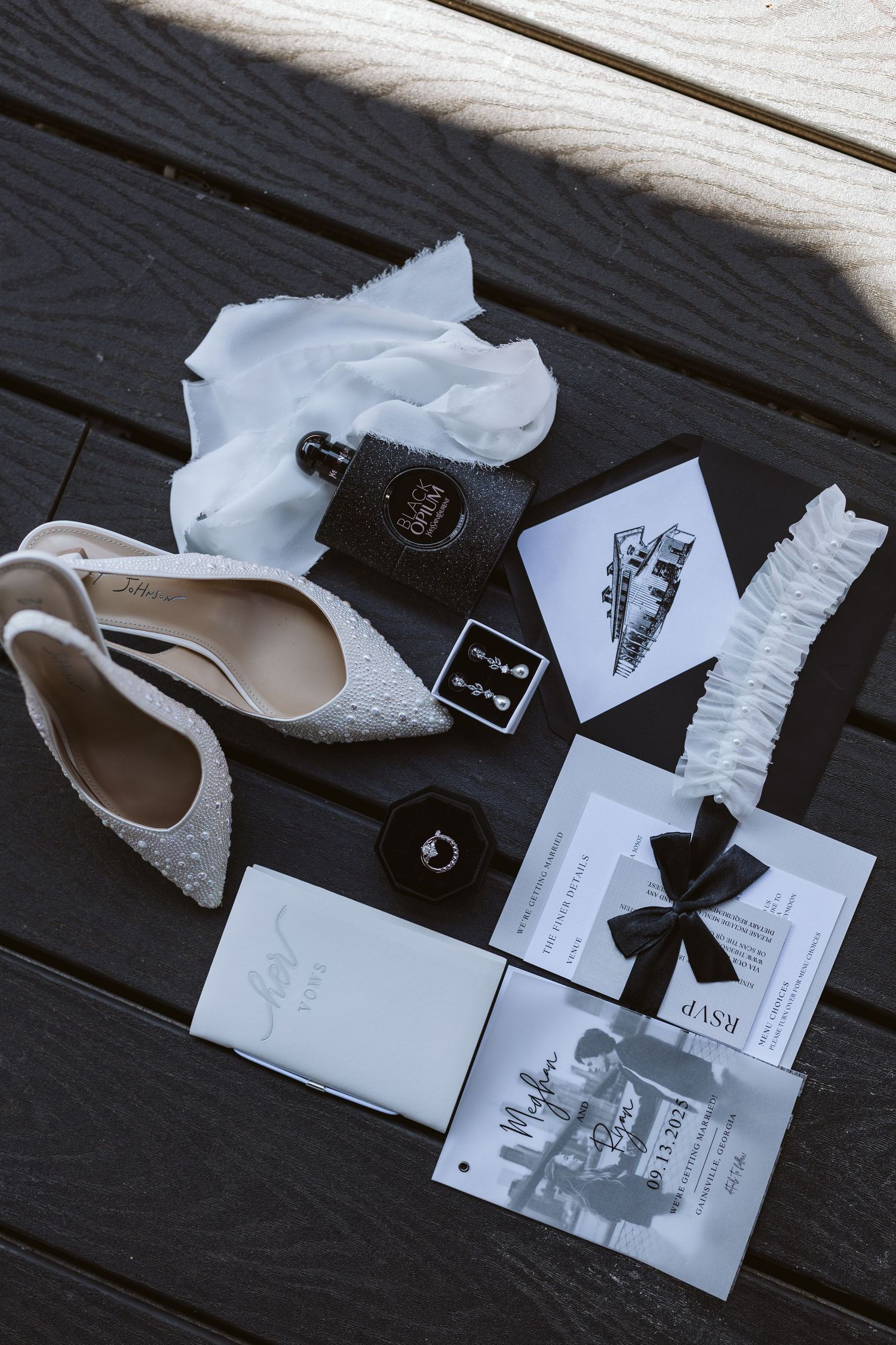 Flat lay of bridal items including heels, purfume, hankie, earrings, garter, etc