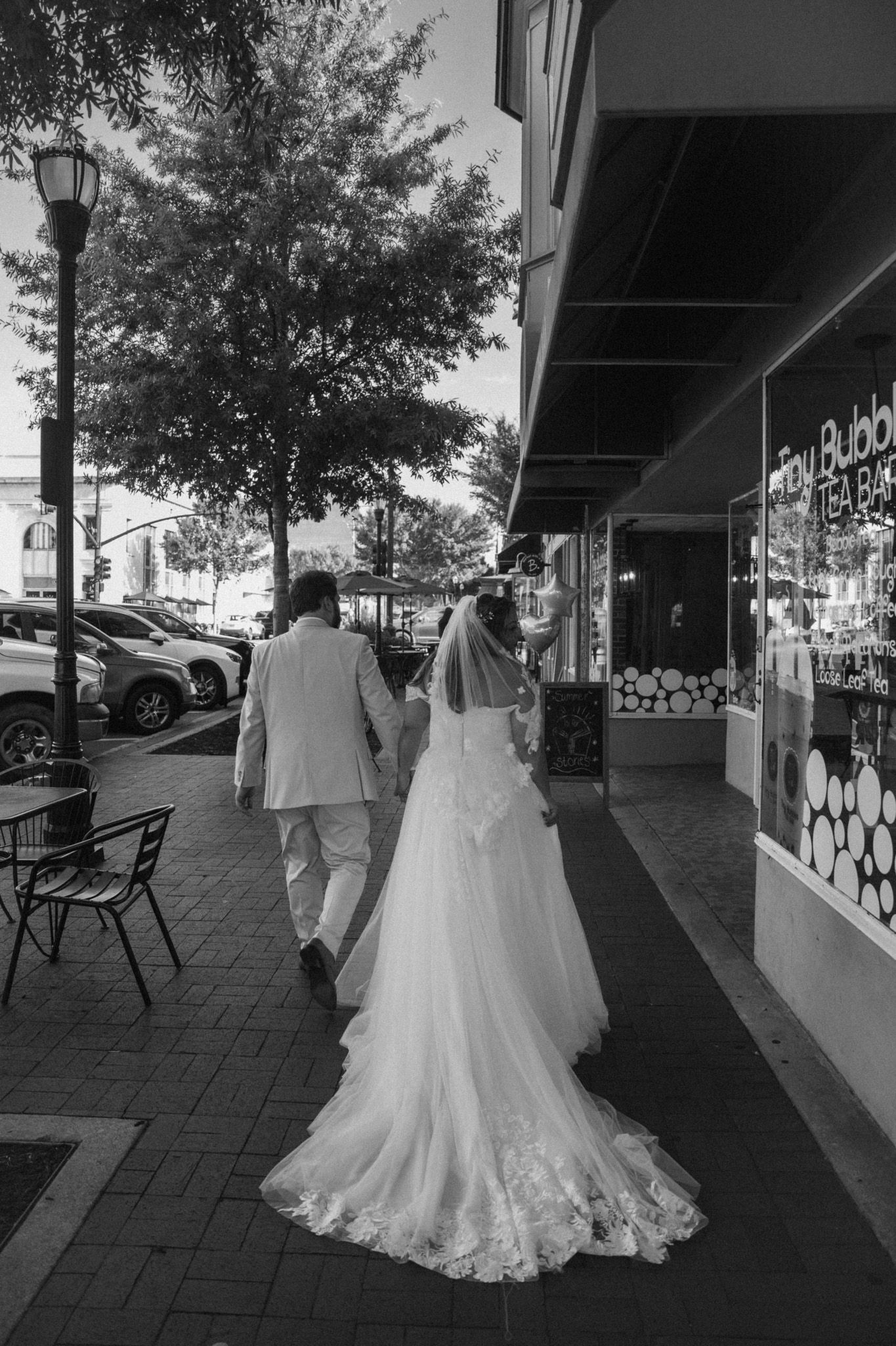 Bride and groom holding hands walking through the town square by the shops