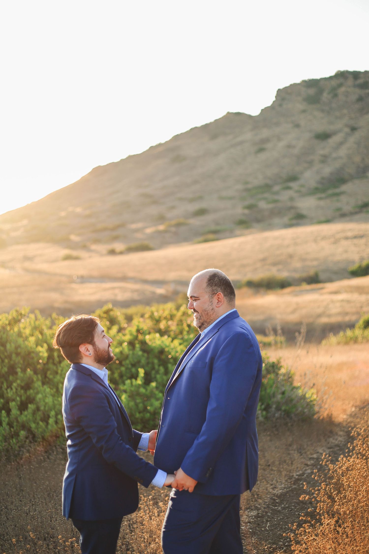 A couple looking into each other's eyes in a field with mountain
