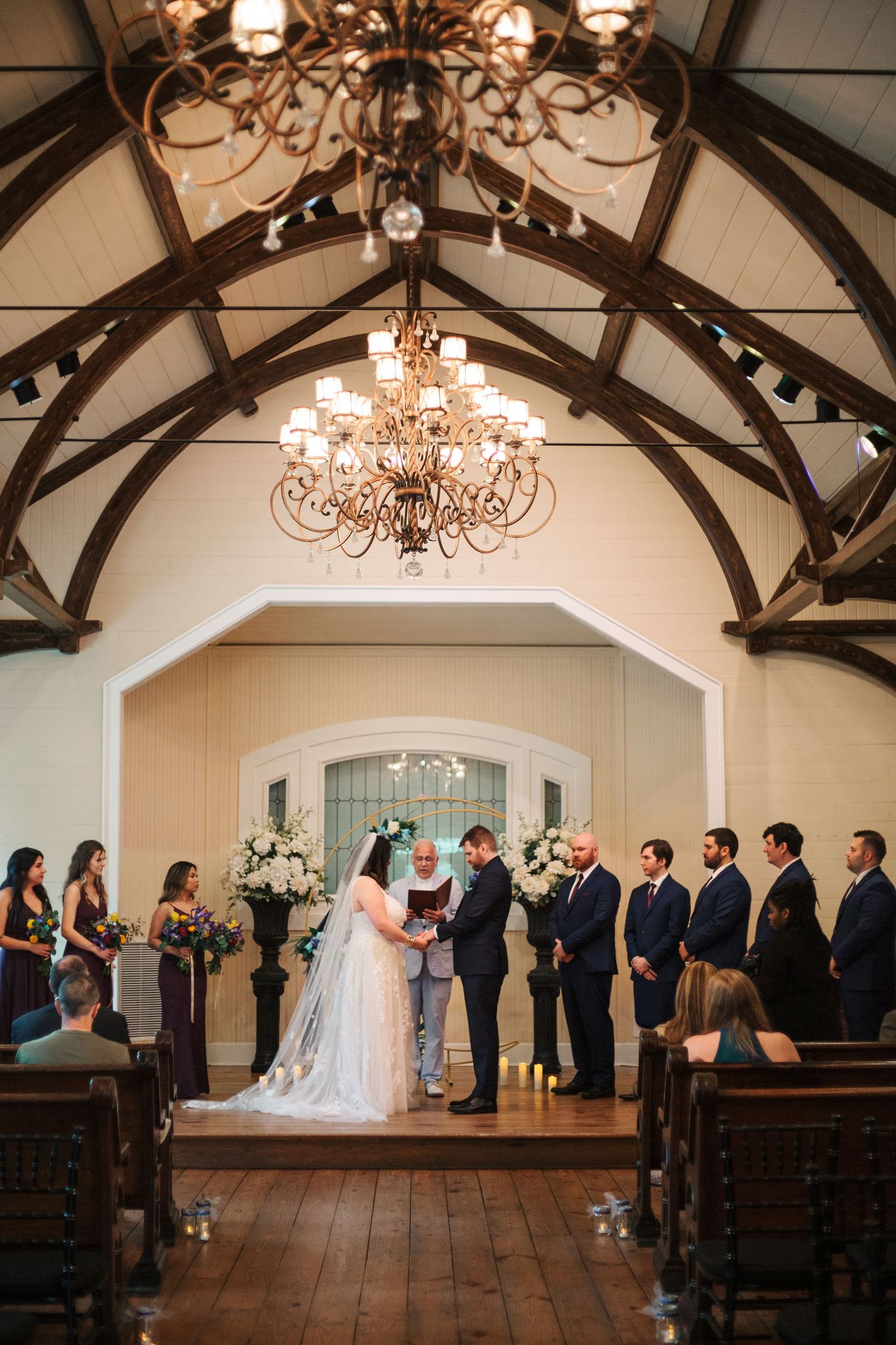 Bride and Groom holding hands during their wedding ceremony surrounded by their wedding party
