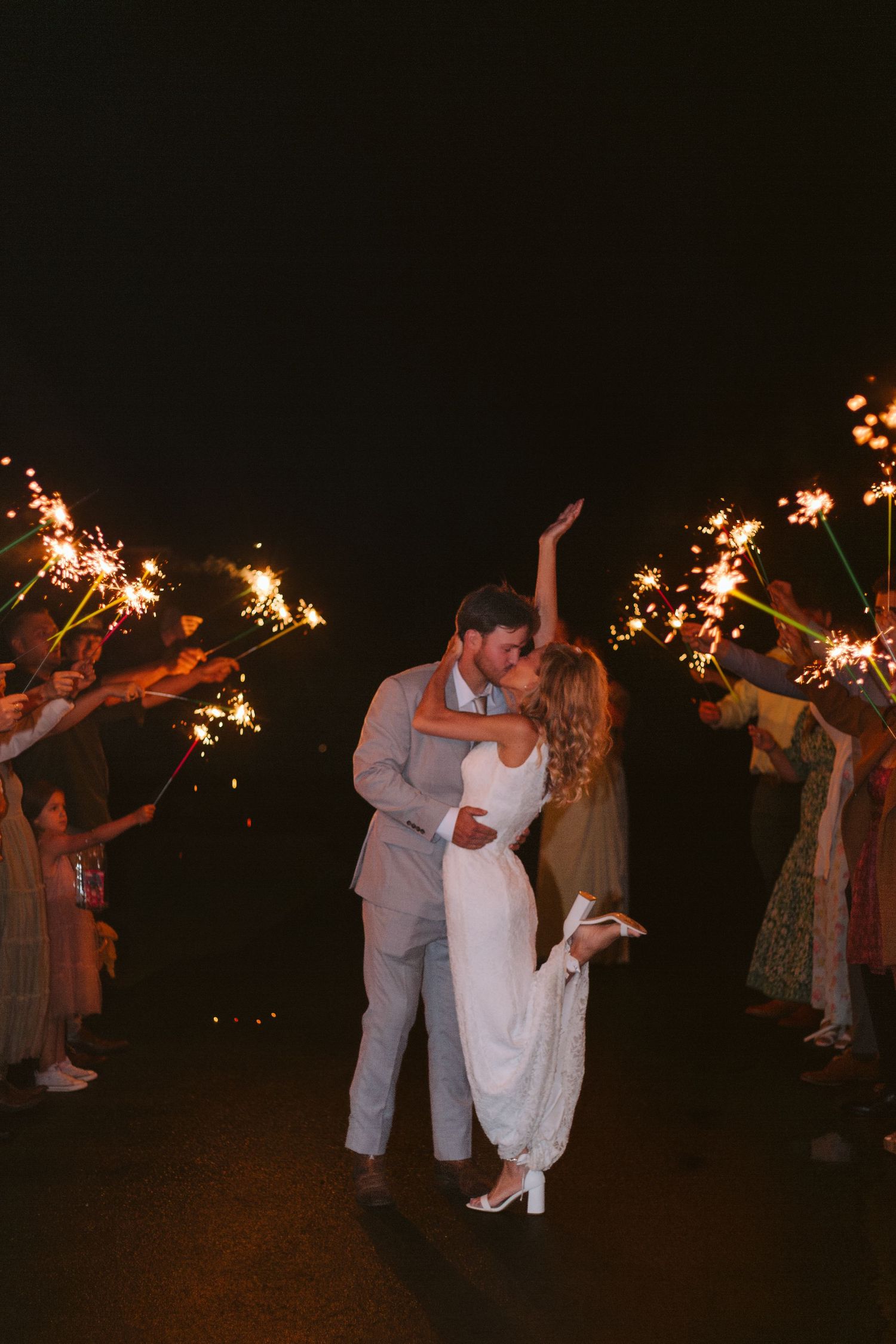 Bride and groom sharing a kiss down the line of onlookers holding sparkers