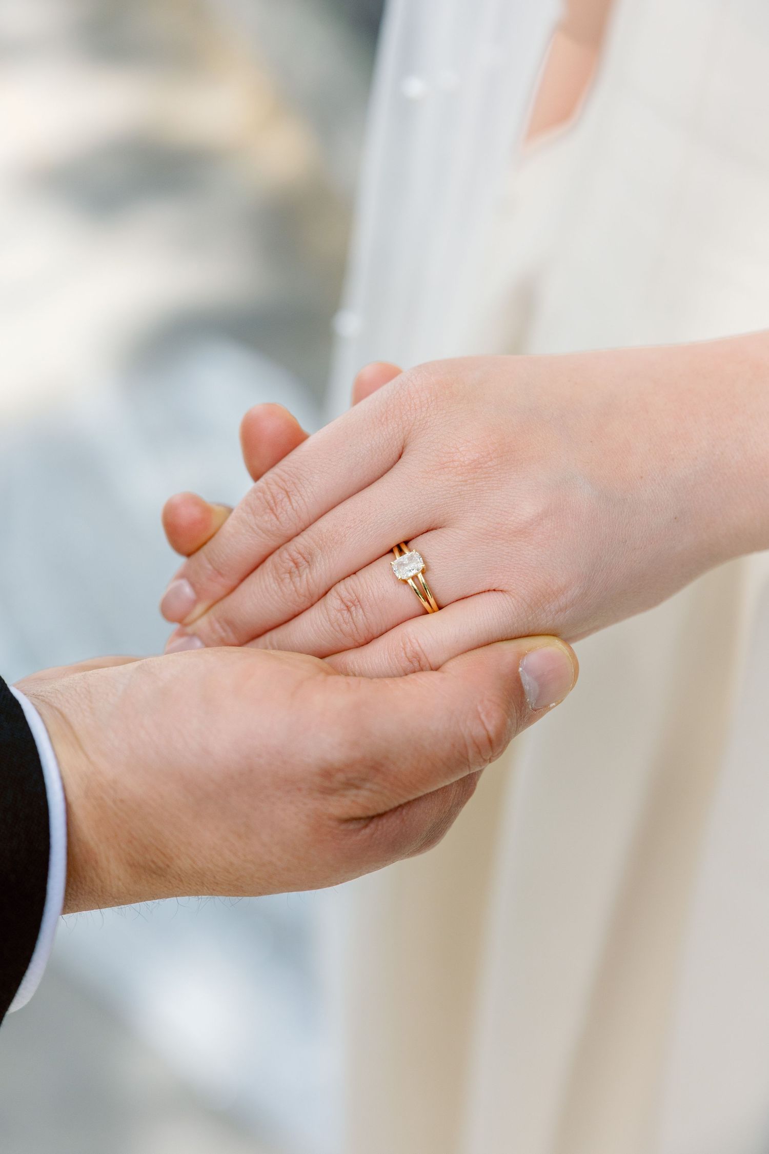 Close-up of bride and grooms hands showing gold diamond engagement and wedding rings.