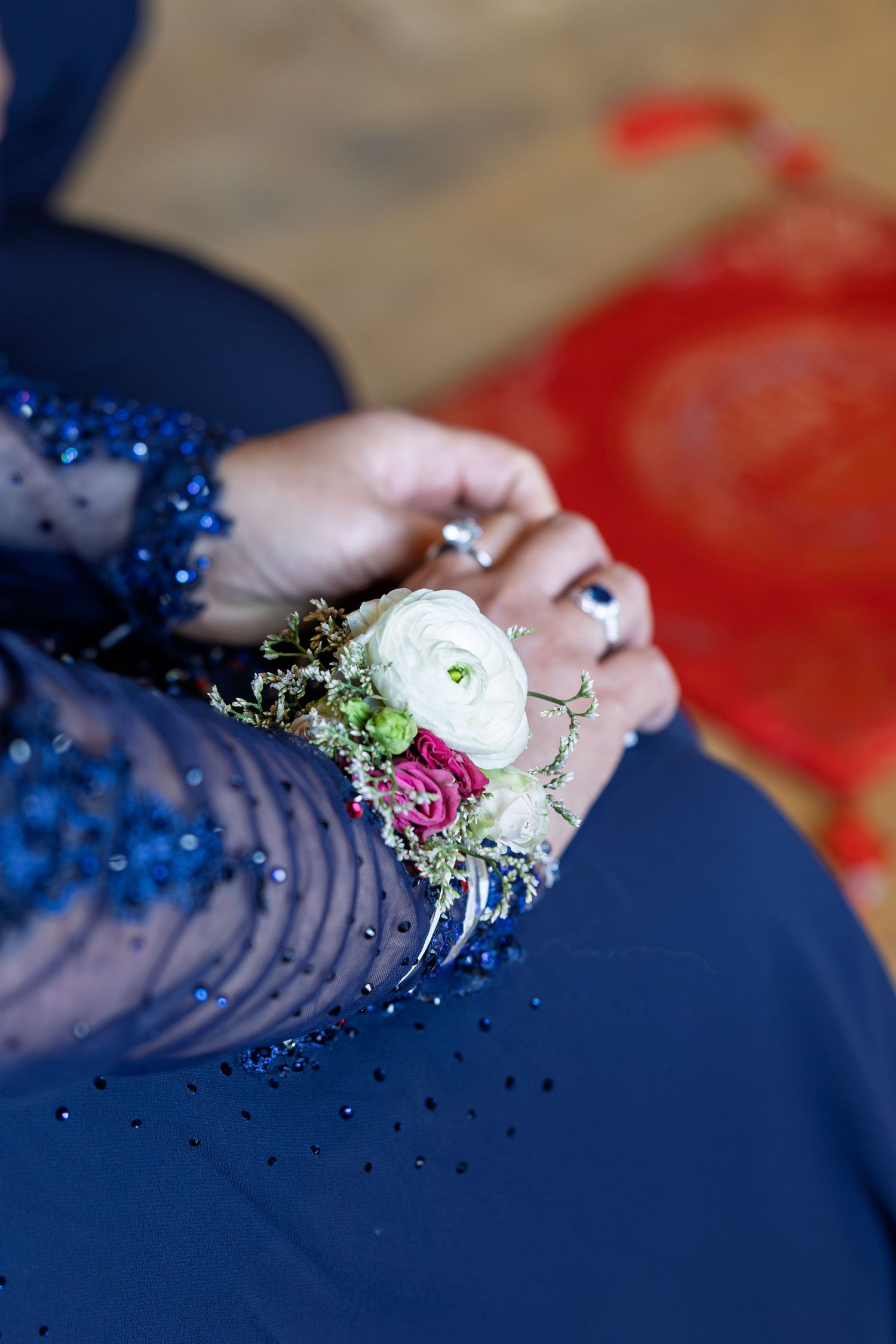 Close-up of a floral wrist corsage with white and pink roses on a blue sequin dress.