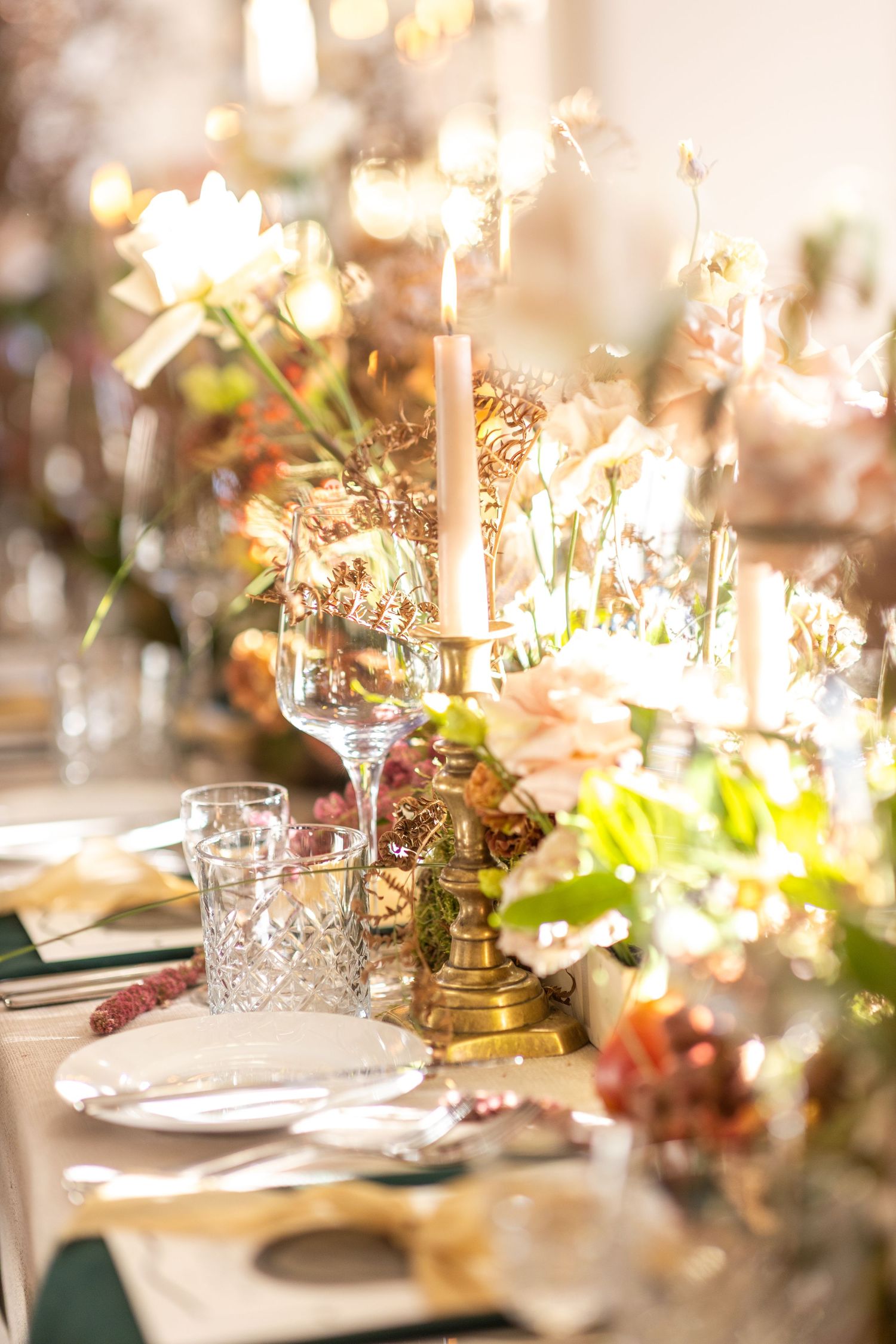Elegant wedding reception table setting with glowing candles and floral arrangements.