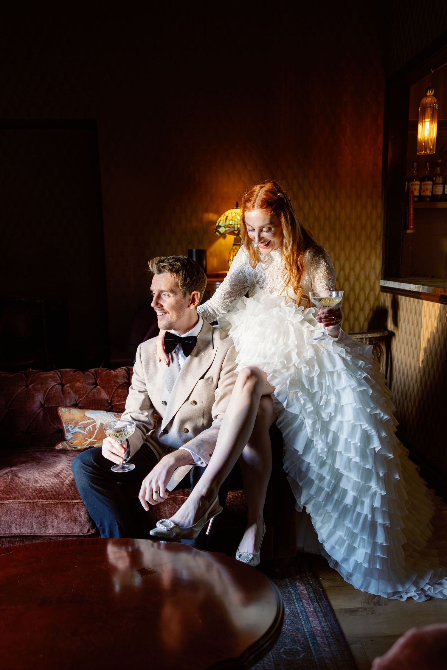 Dramatic moody wedding photo sequence showing couple in formal attire seated in dark room with glowing lamp.