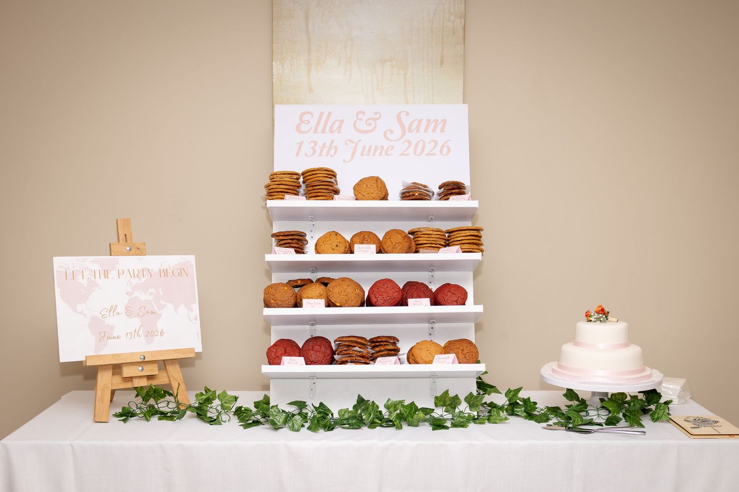Wedding dessert table featuring a donut wall and white cake with Ella and Sam June 2026 sign.