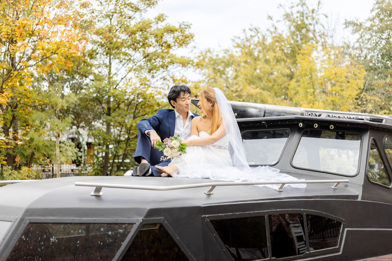 Romantic wedding photos taken with classic car against autumn foliage background.