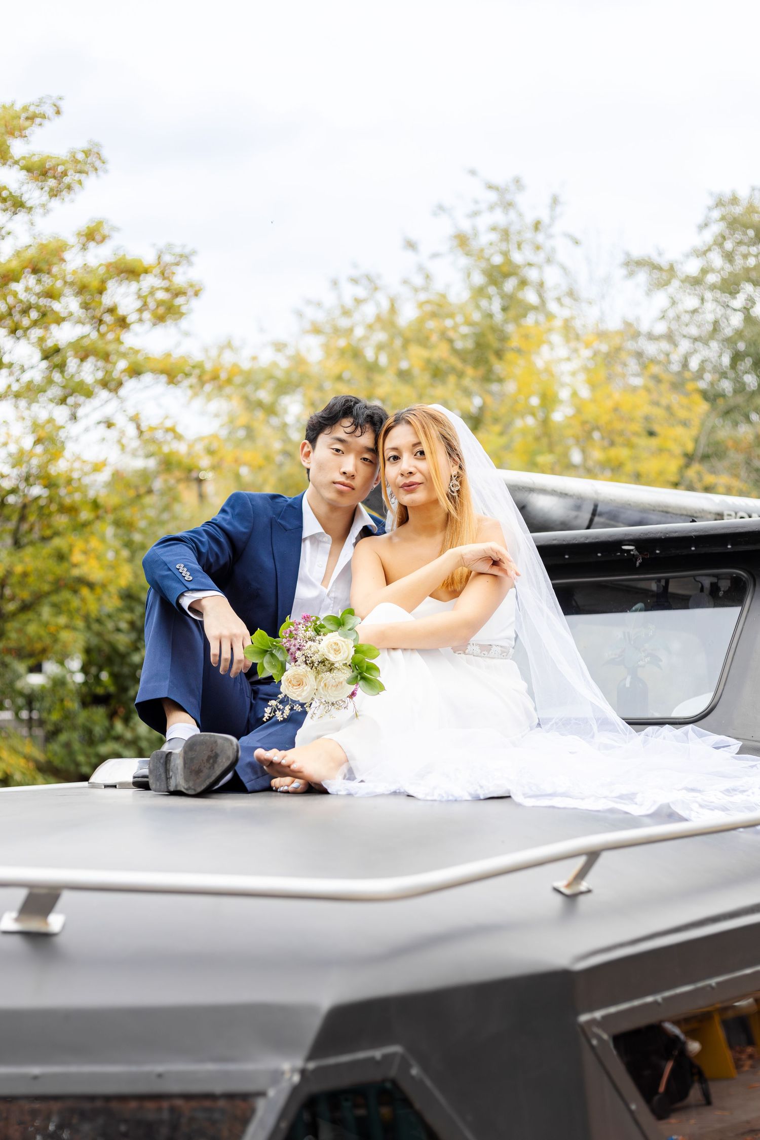 Newlyweds pose together in vintage convertible car during autumn wedding photoshoot.