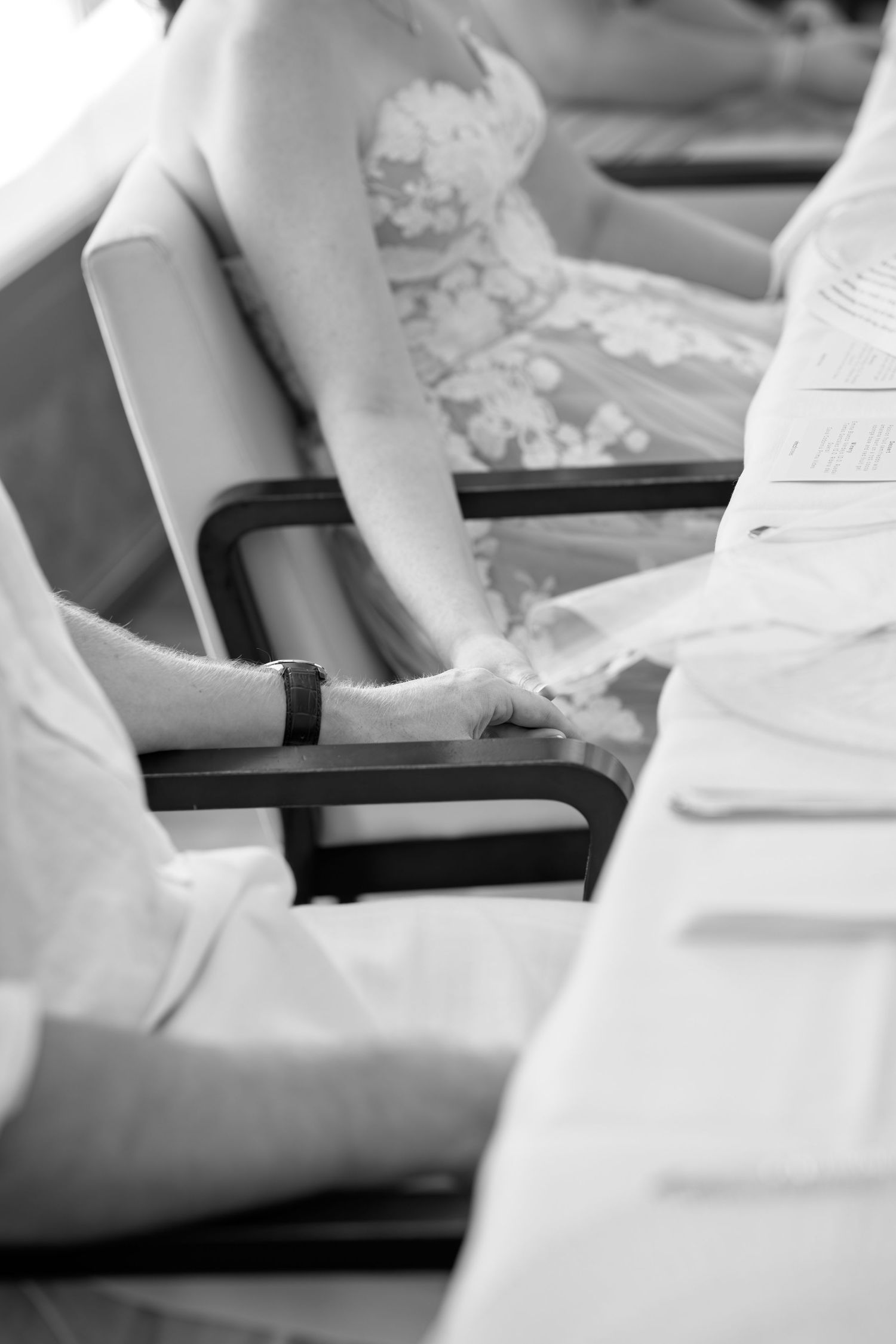 Black and white photo of bride and groom holding hands during wedding ceremony.