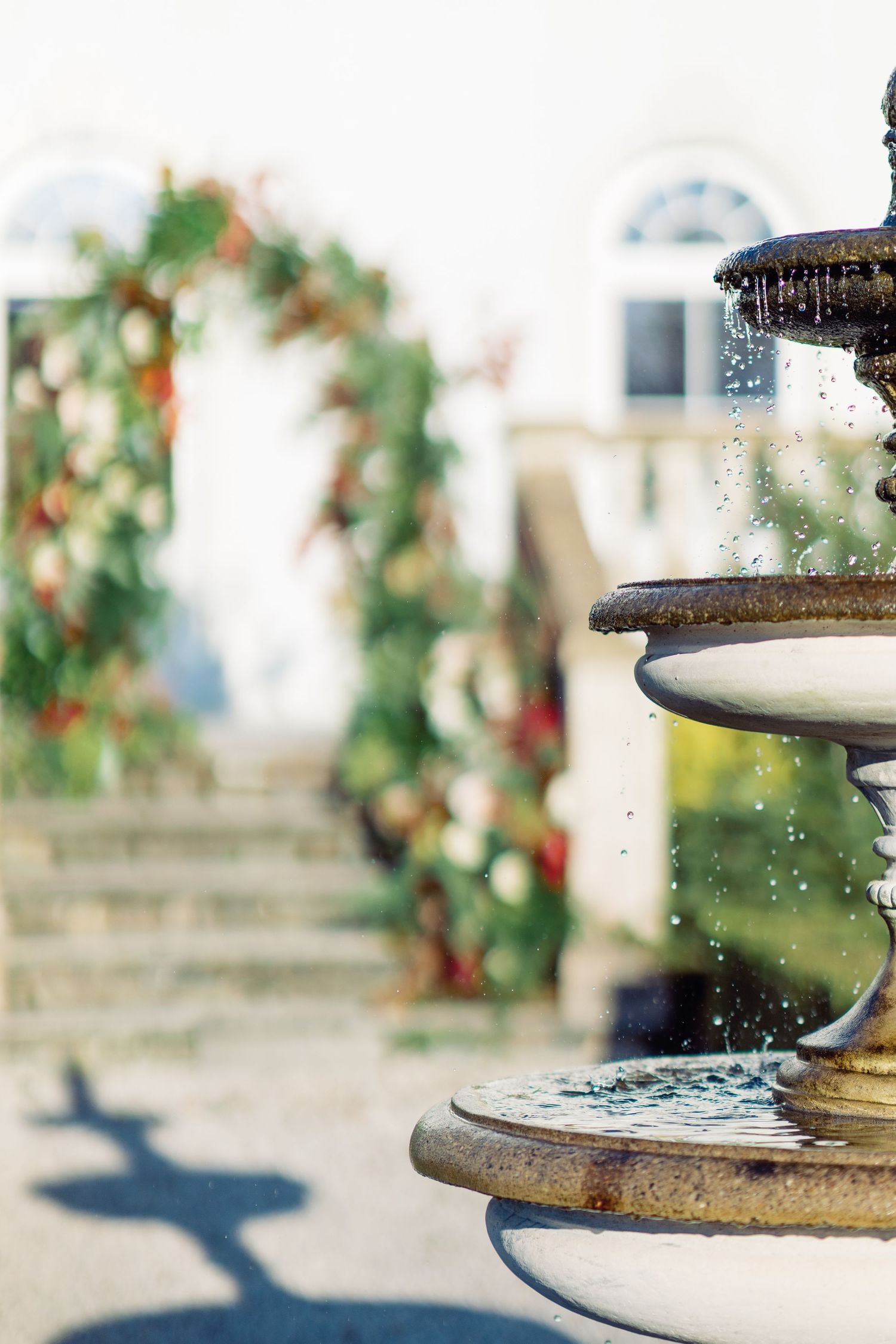 Water droplets splashing in sunlit fountain with blurred garden background.