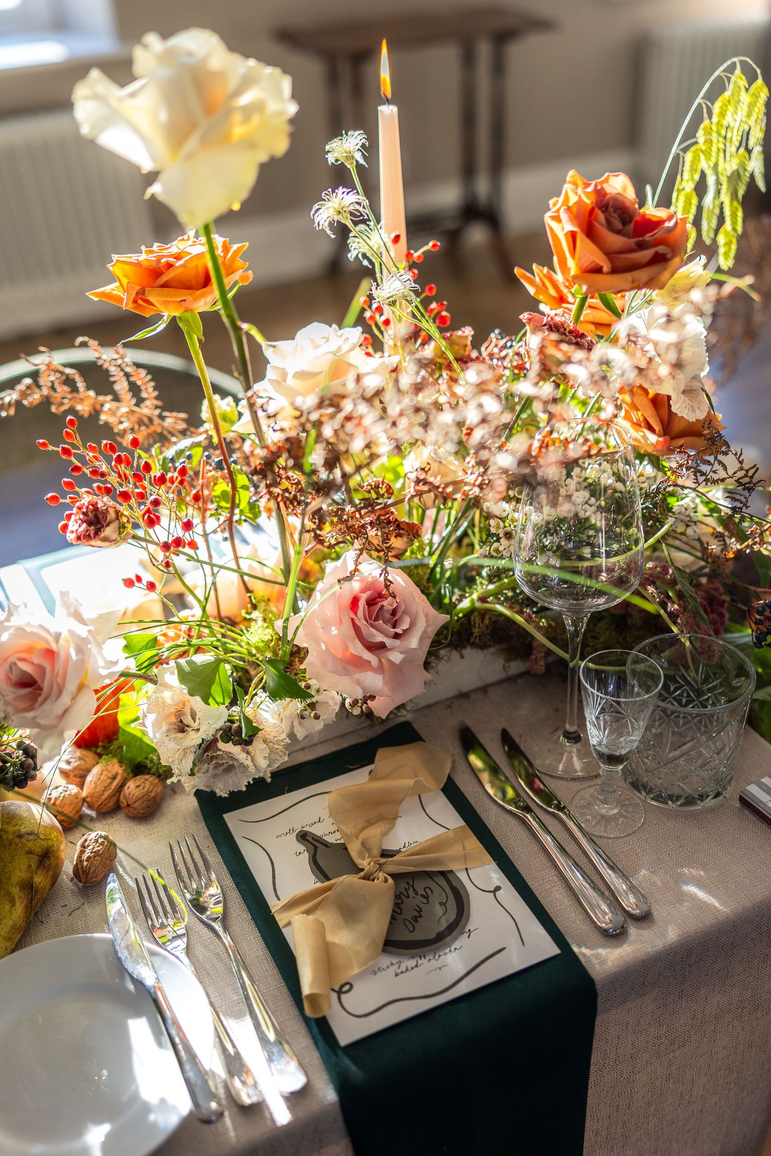 Elegant wedding table decorated with pink roses, candles and floral centerpieces in soft natural lighting.