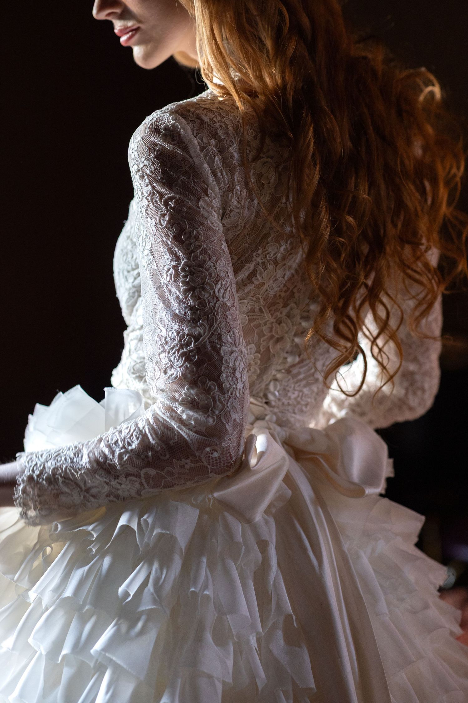 Side view of wedding dress highlighting delicate lace bodice and layered tulle skirt.