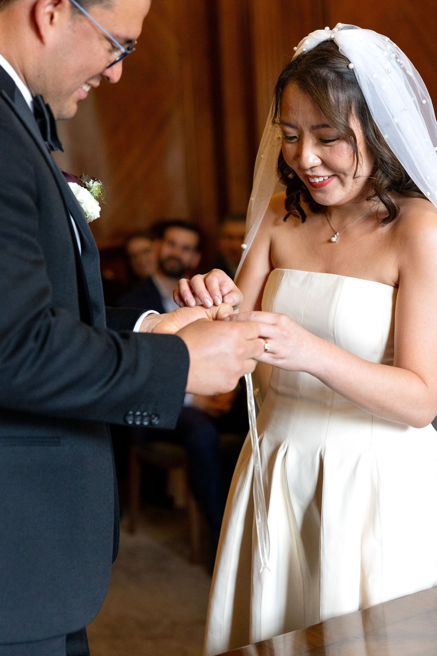Bride smiles as couple exchanges wedding rings during intimate ceremony.