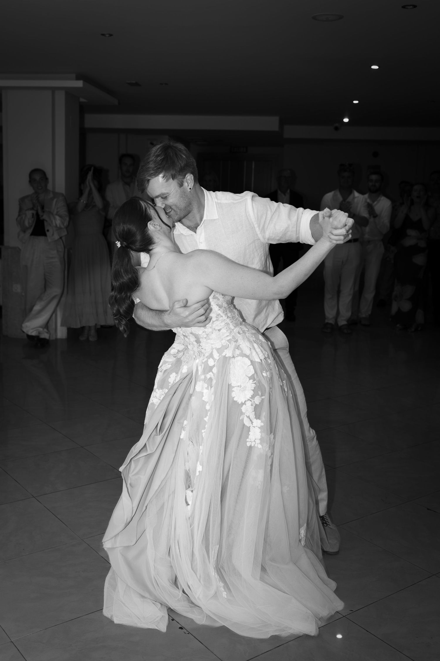 Elegant black and white photo of bride and groom sharing romantic first dance at wedding reception.