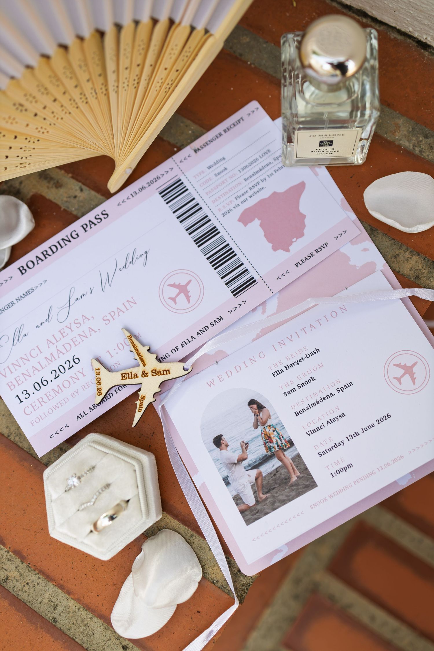 Elegant destination wedding stationery including boarding pass invitations, rings, and accessories on terracotta tiles.