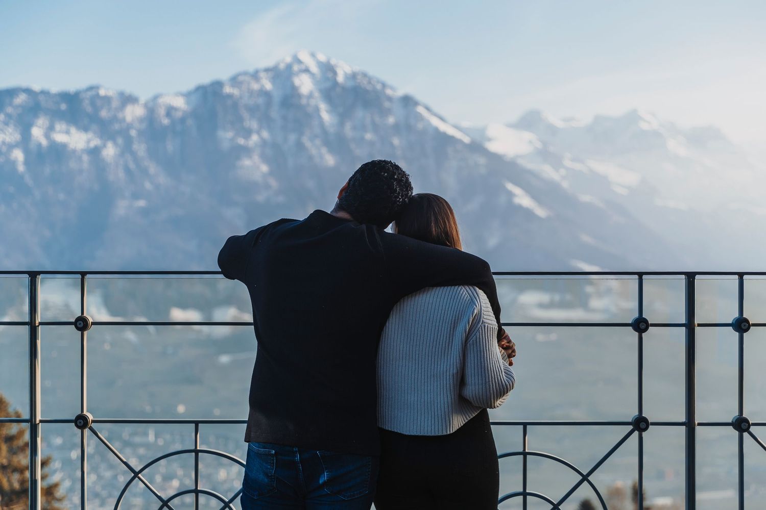 Silhouetted figures against majestic mountain landscape with snow-capped peaks.