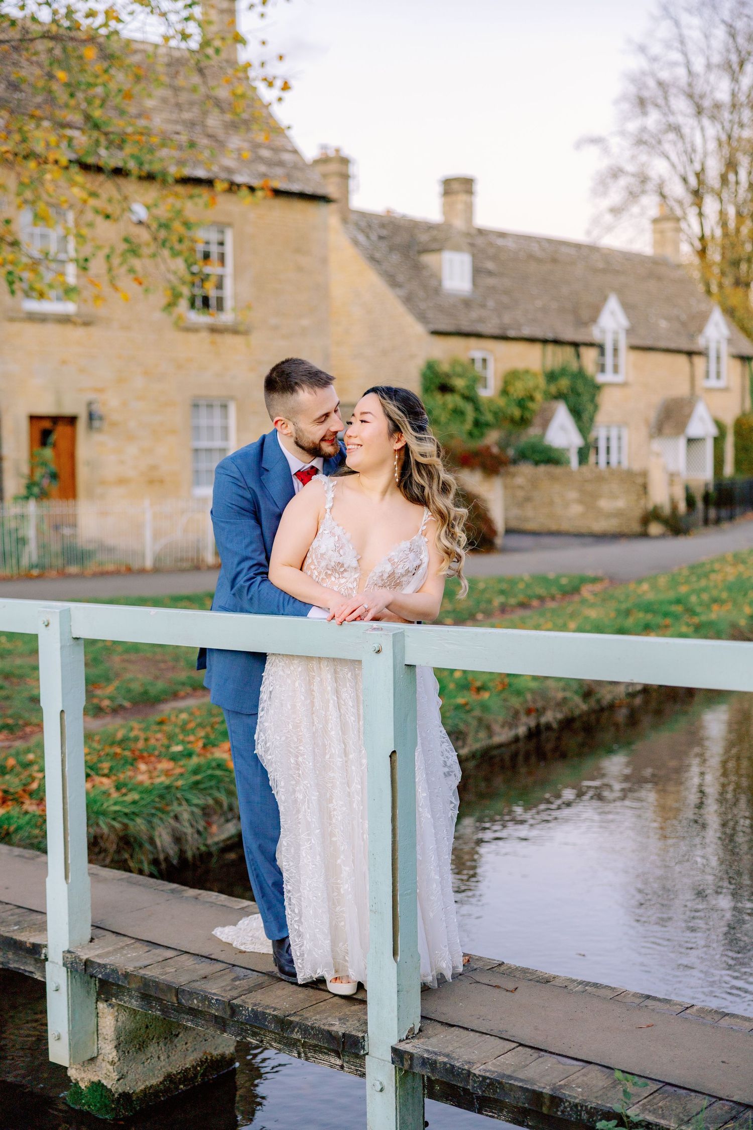 Newlyweds share intimate moments on a wooden bridge over a canal during their autumn wedding.