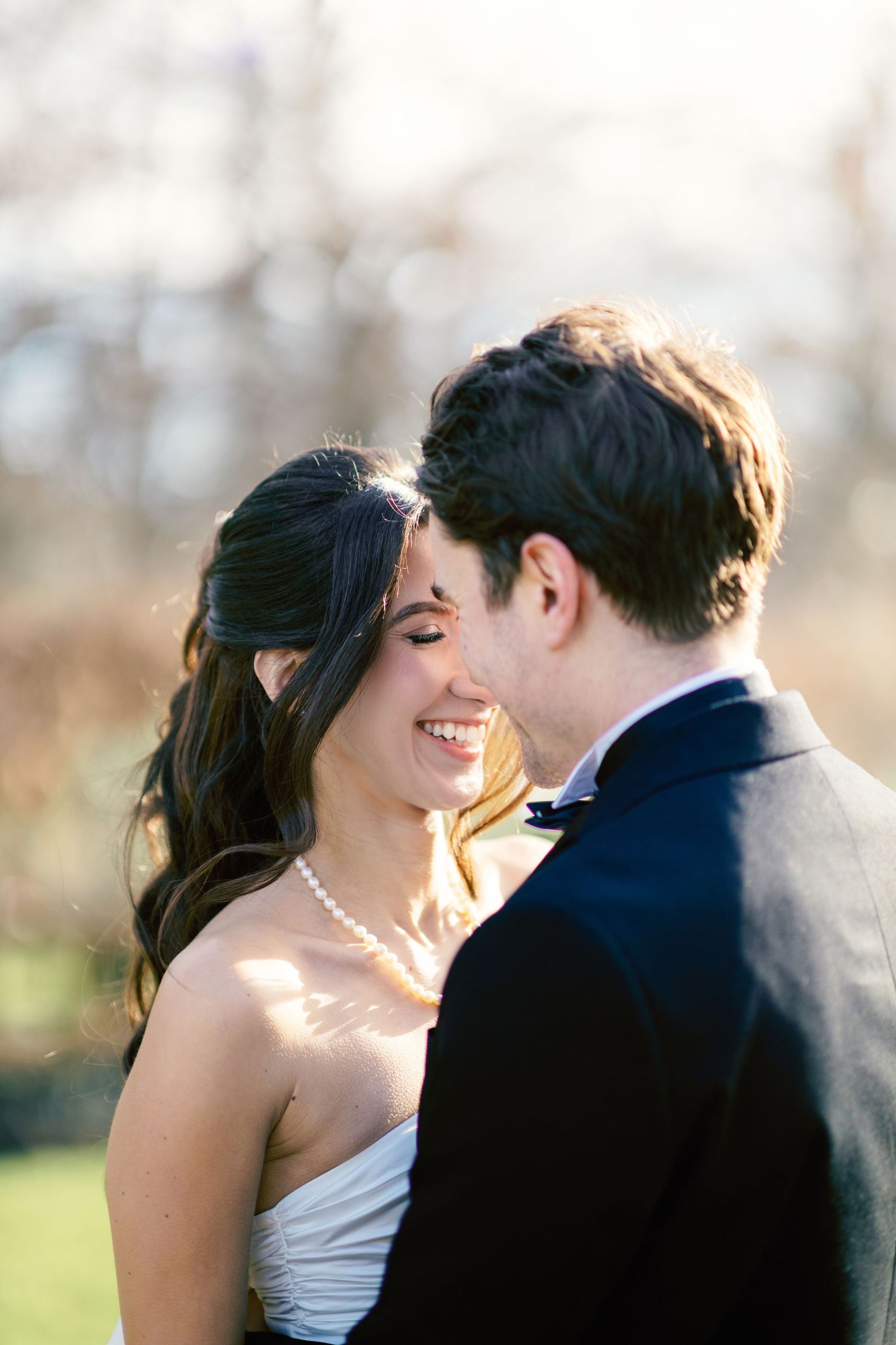 A romantic moment captured between a couple in formal attire sharing tender kisses outdoors at sunset.