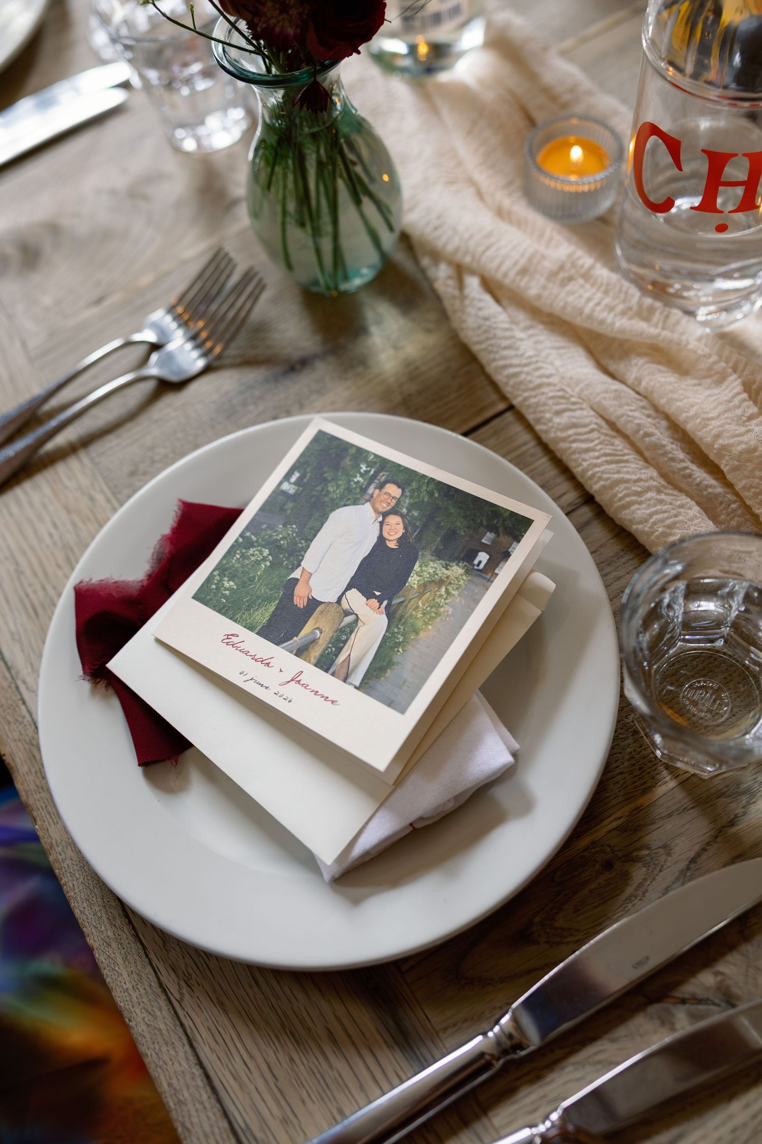 Wedding place setting with Polaroid photo of couple on white plate at rustic reception table.