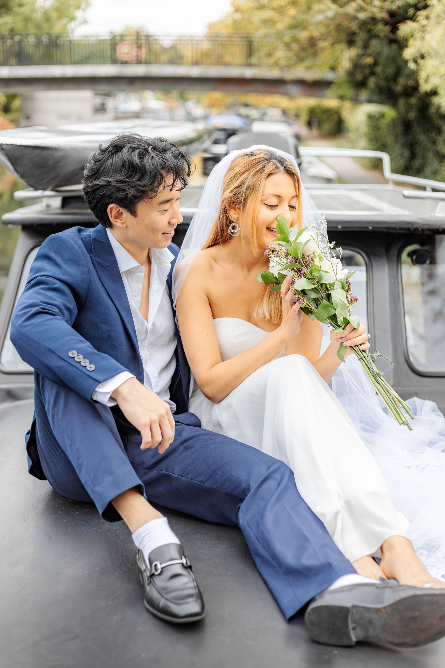 Wedding couple lounges on vintage car hood during outdoor autumn photoshoot.