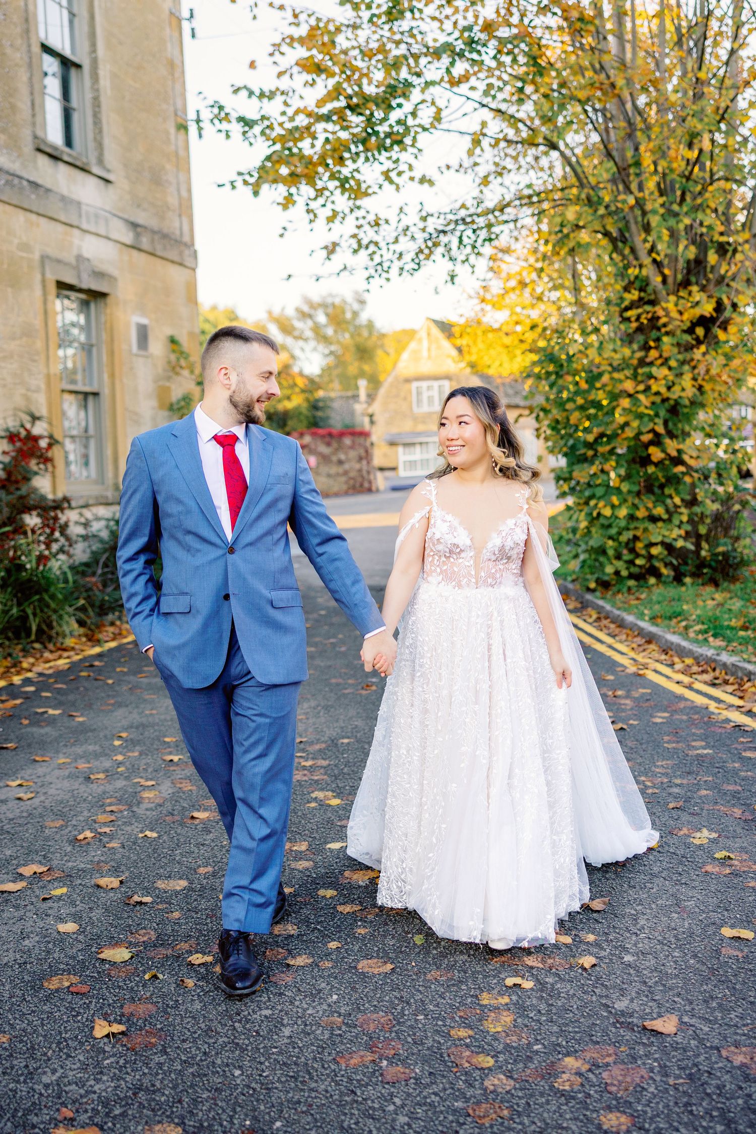 Wedding couple walking together on path surrounded by fall colors.