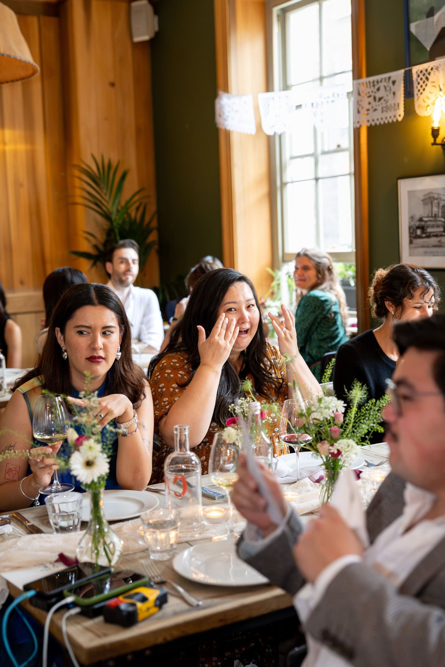 Emotional wedding guest wipes tears during heartfelt reception speeches at rustic venue.