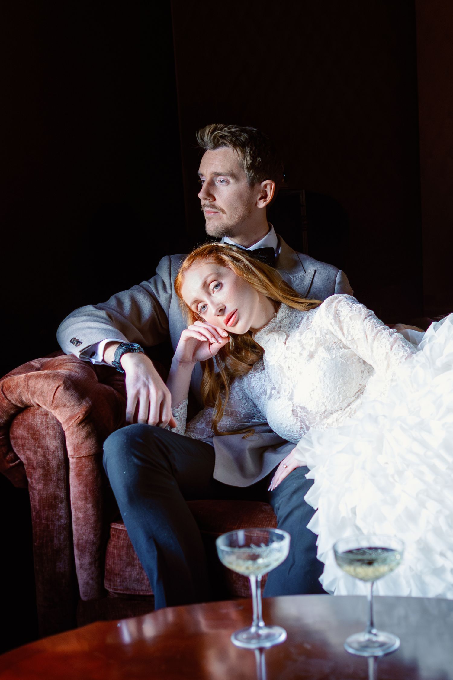 Romantic portrait sequence on vintage couch with dramatic lighting and formal attire.