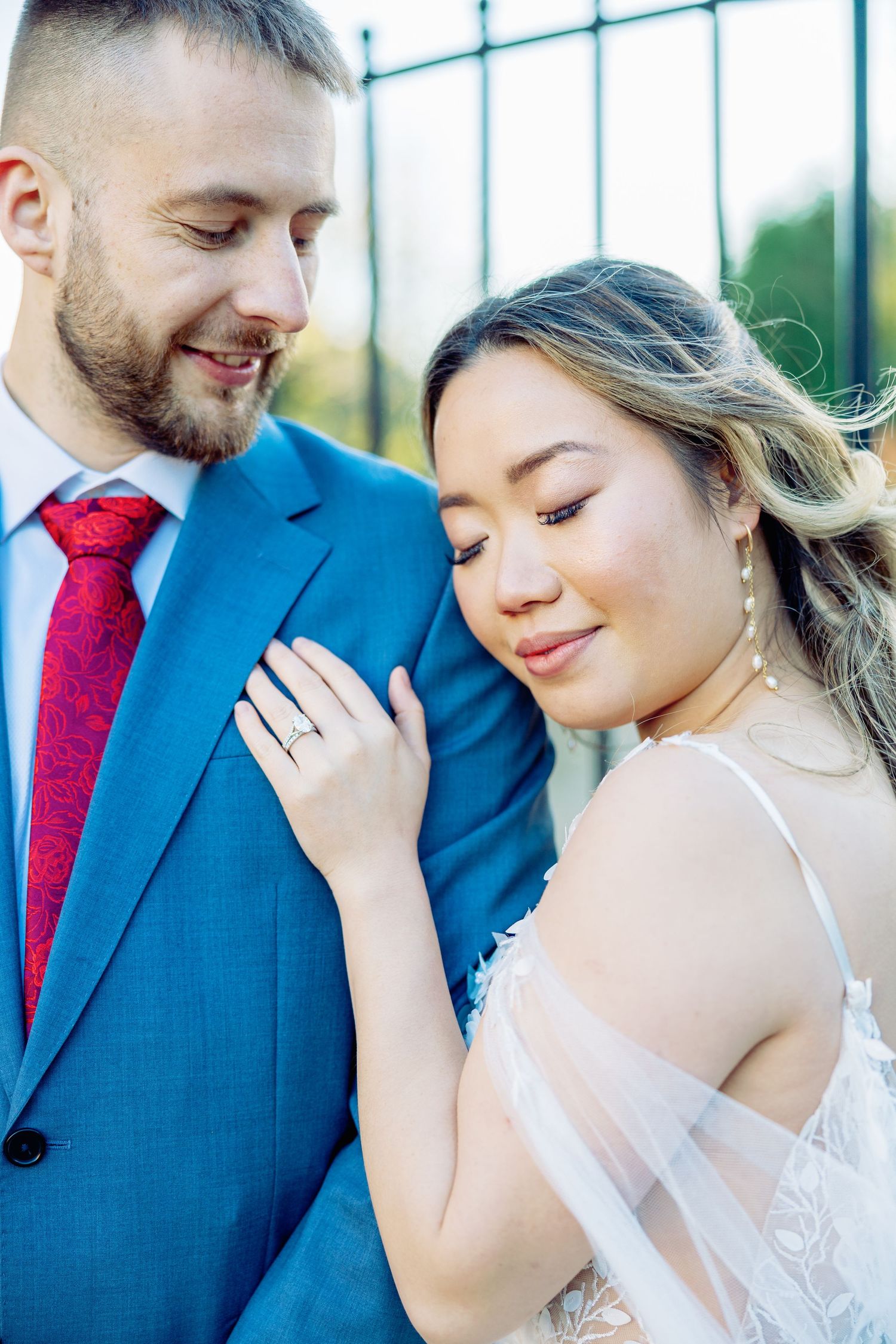 Intimate wedding portraits against iron gates in soft lighting.
