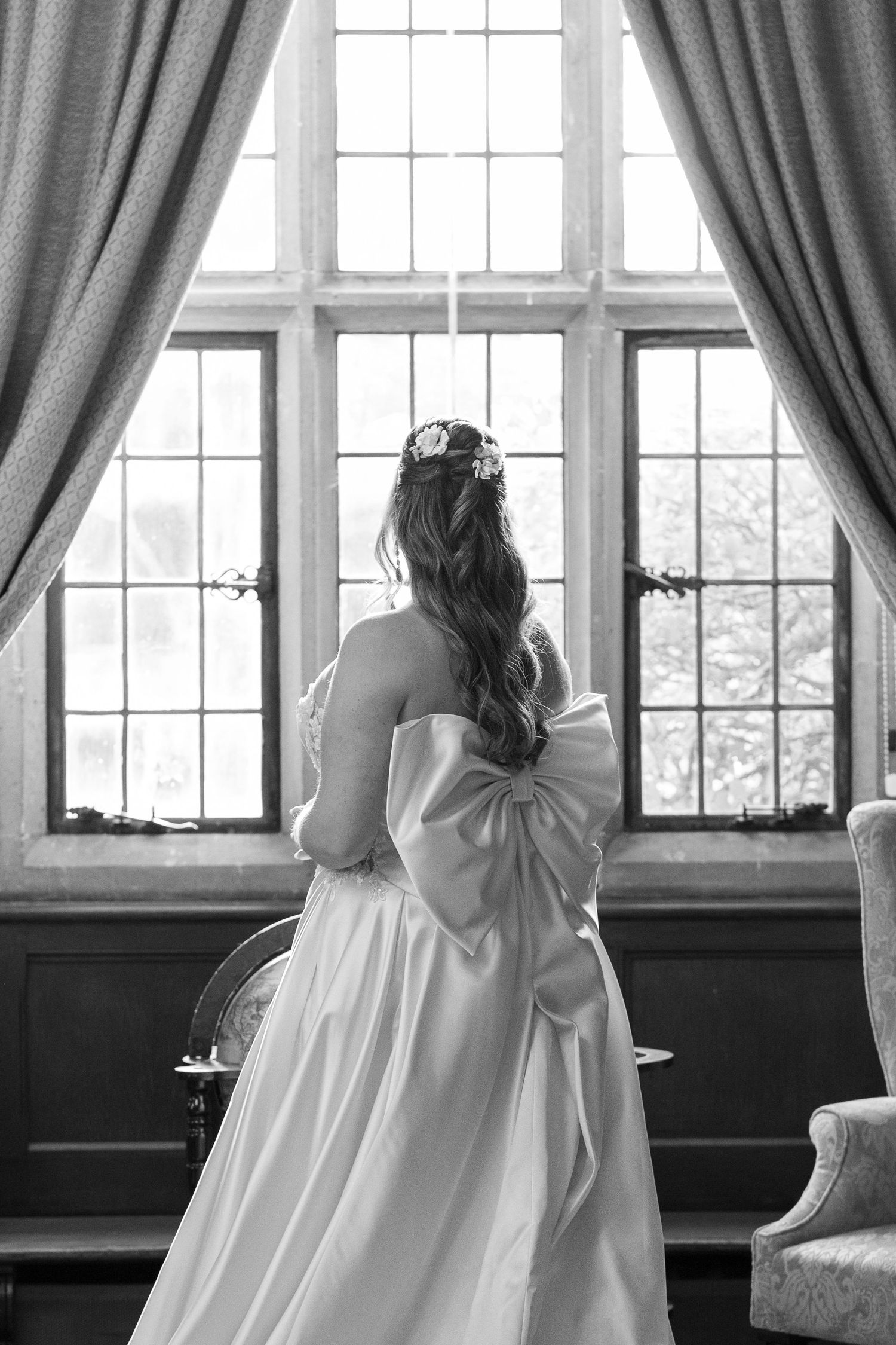 A black and white panoramic series shows a person in a white dress looking through windows in an elegant room.