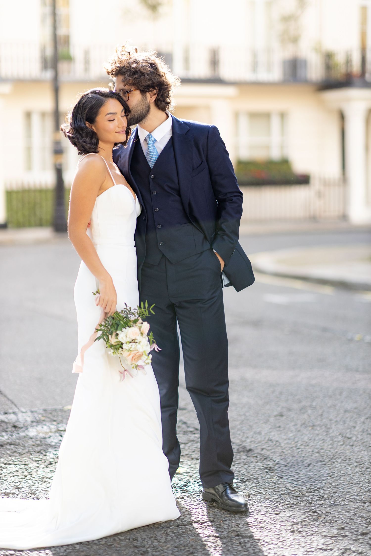 Wedding couple shares intimate moment on cobblestone street.