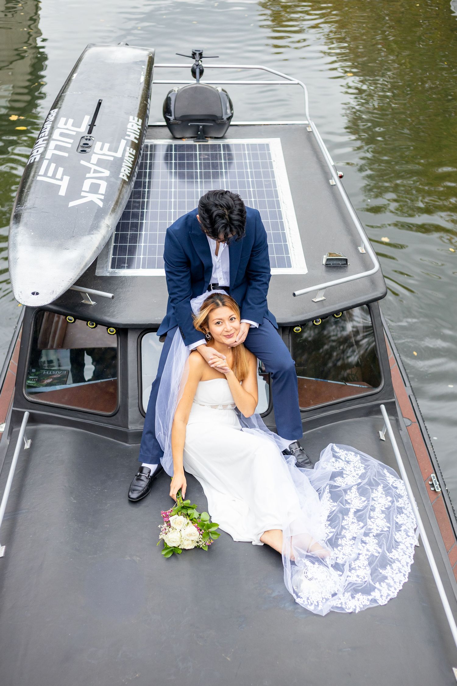 Wedding couple poses on solar-powered boat deck in romantic photoshoot.